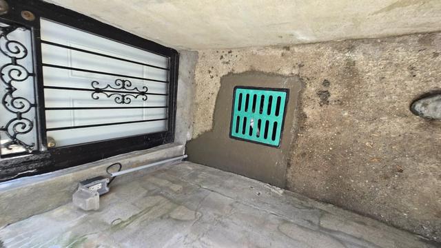 New drain grate set into a parged concrete wall at a basement entrance
