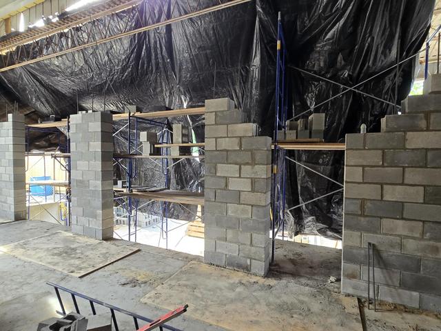 New block walls with openings formed, under protective sheeting and scaffolding
