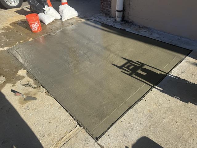 Second view of a freshly poured broom-finish concrete slab next to a building