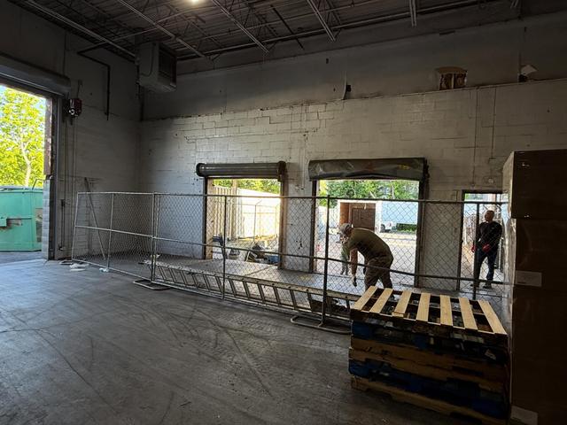 Inside a commercial building during wall demolition, with open loading bays and a worker on site