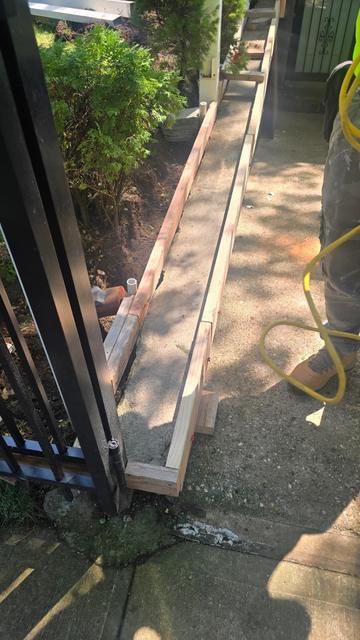 Wood forms set for a new poured concrete wall cap along a side walkway