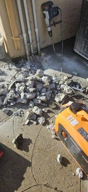 Broken concrete pieces and a jackhammer during demolition beside a building