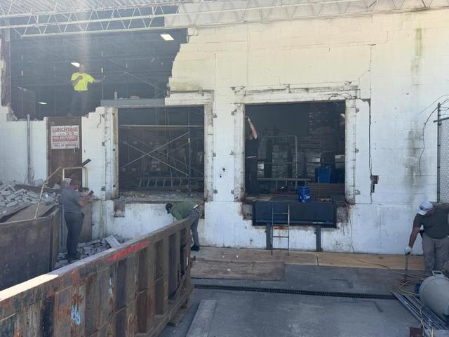 Exterior loading dock wall with window openings and scaffolding before demolition
