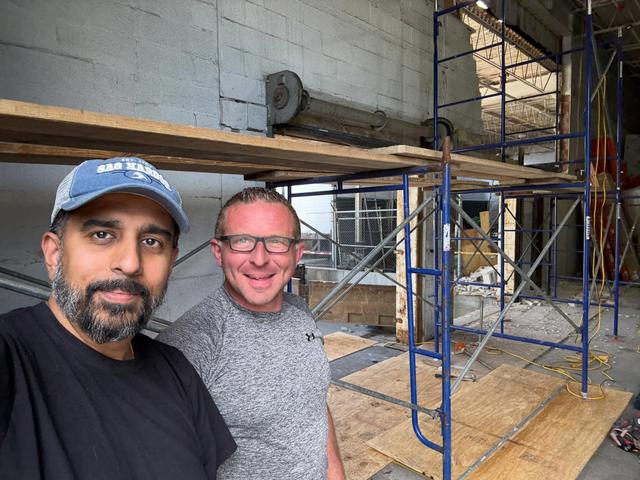 Two members of the Masoncrete Builders team on site in front of scaffolding during a block wall rebuild