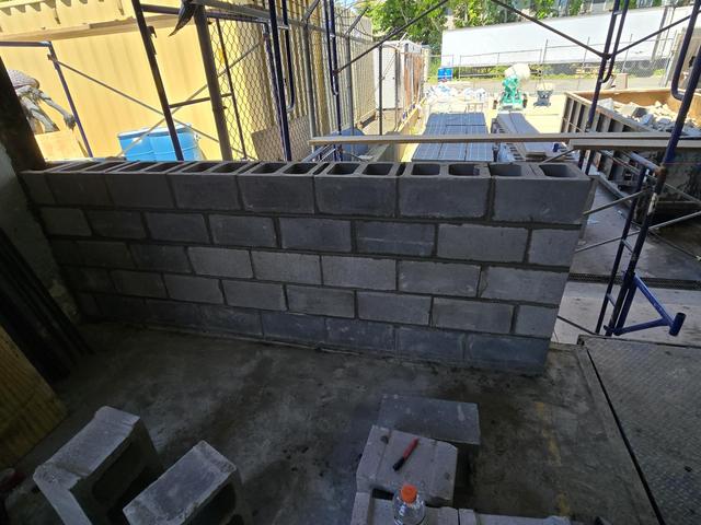 First courses of a new concrete block wall going up beside scaffolding