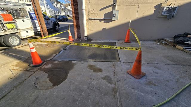 New concrete section taped off with caution tape and cones while it cures beside a building