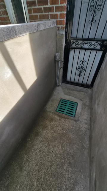 New concrete floor and drain grate at a basement door