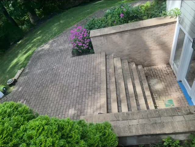 Brick paver patio with wide steps down to a lower landing beside a low brick-faced wall