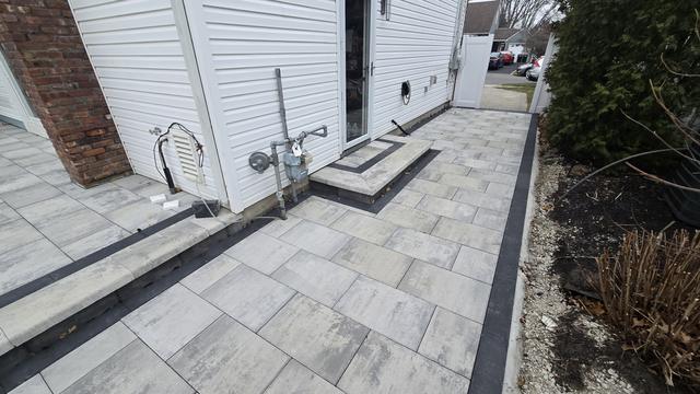 Porcelain paver side yard with a dark border and a step up to the house