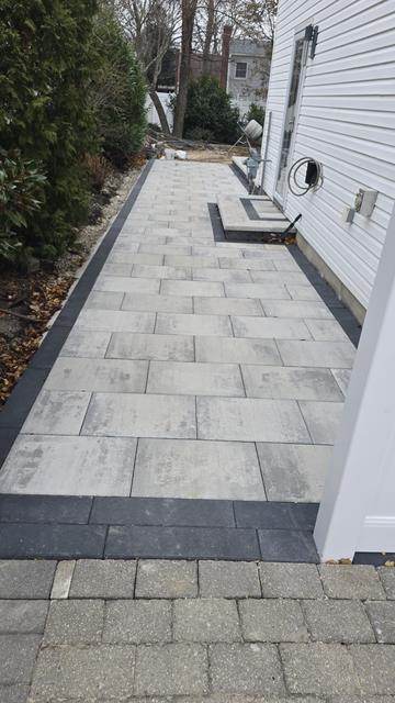 Porcelain paver walkway with a charcoal border alongside a house, meeting a paver landing