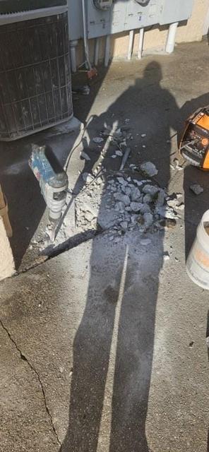 Saw-cut and broken concrete being removed along a building wall