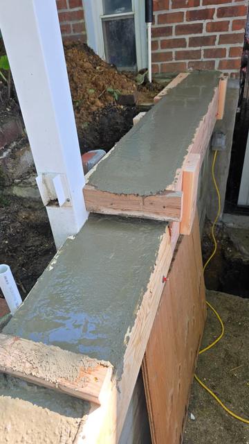 Freshly troweled concrete wall cap next to a white porch column